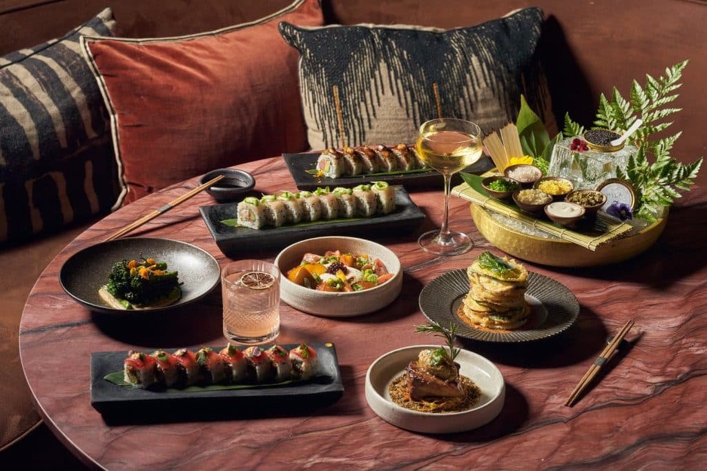 Elegant dining table at MILA Miami Beach with sushi rolls, caviar, cocktails, and modern small plates in a luxury lounge setting.