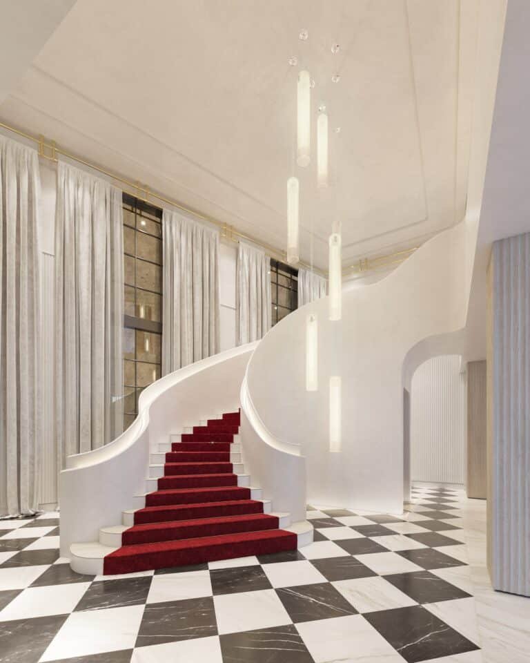 Grand staircase with red carpet at Baccarat Residences Brickell, featuring marble floors and pendant lighting in the lobby.