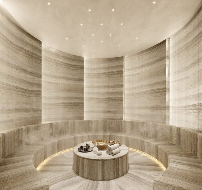 Circular steam room at Baccarat Residences Brickell with natural stone walls, bench seating, and a central table with spa essentials.