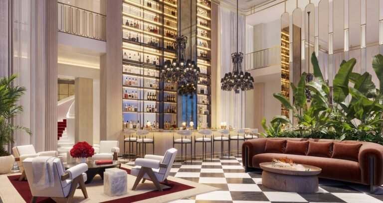 Elegant grand salon bar at Baccarat Residences Miami with high ceilings, chandeliers, and illuminated bottle display.