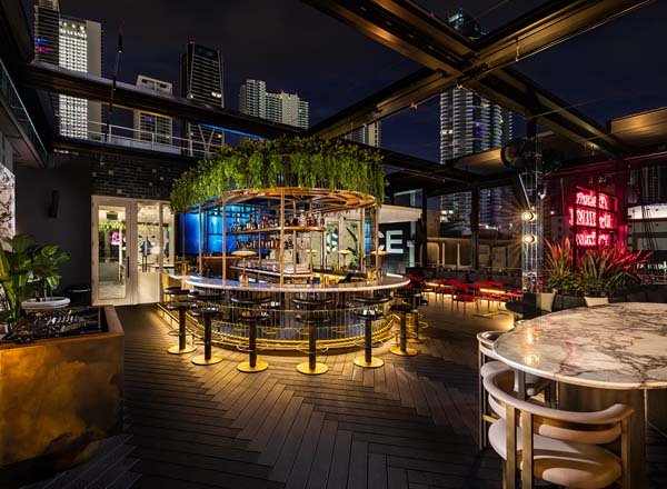 Rooftop bar at Giselle Miami featuring circular bar, modern furniture, and city skyline views at night.