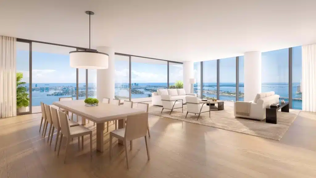 Open dining and living area surrounded by floor-to-ceiling windows with bay views.