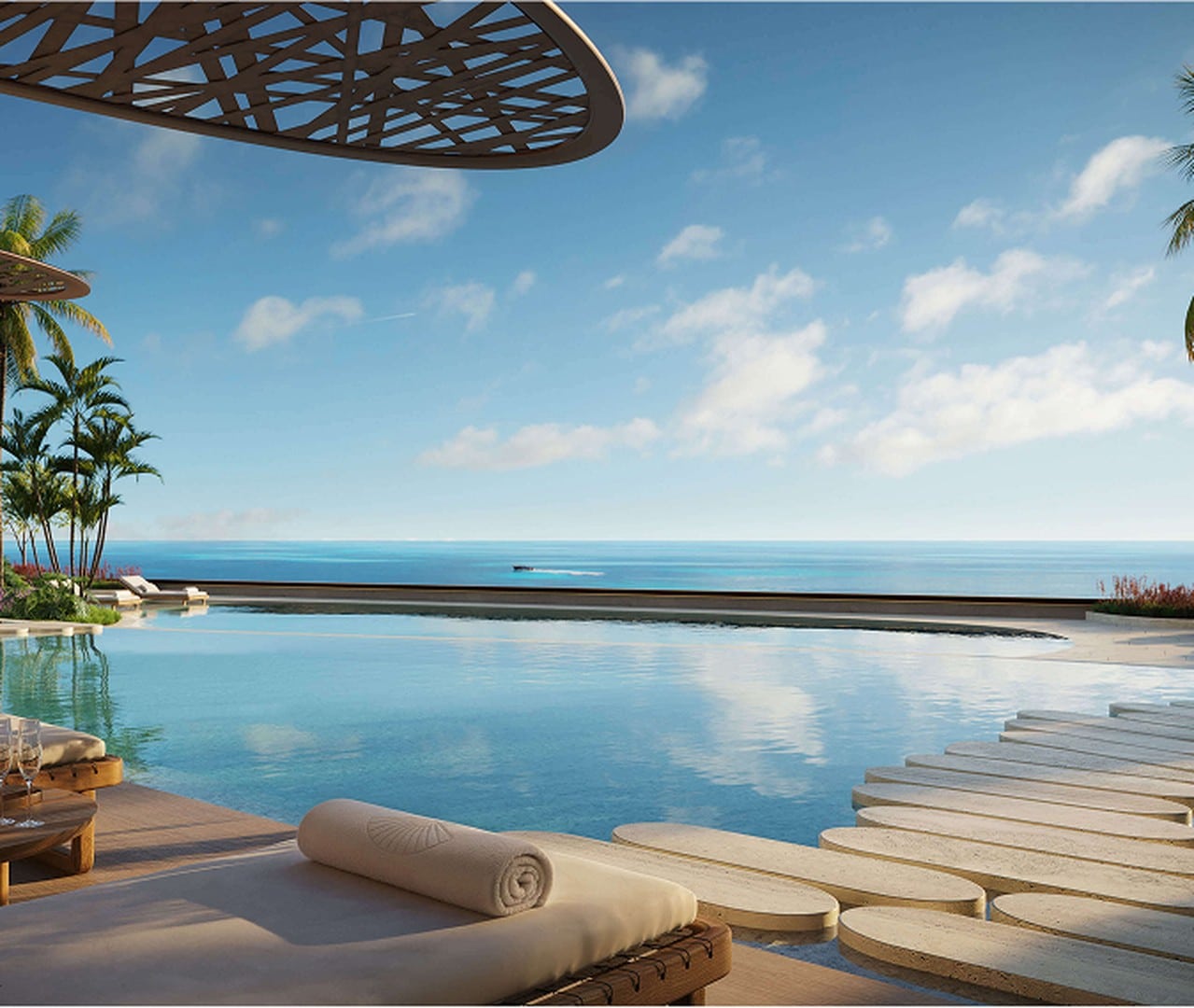 Luxurious poolside scene featuring a serene infinity pool overlooking the ocean, with lounge chairs, palm trees, and a fruit platter, under a clear blue sky.