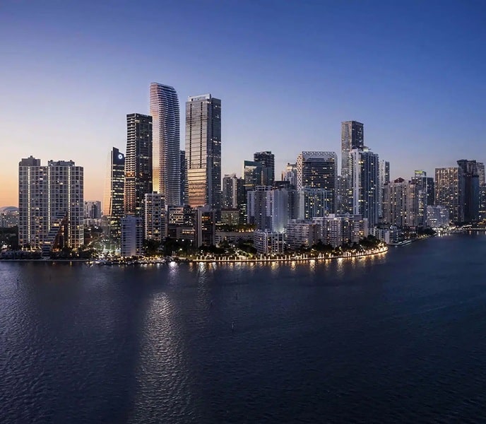 Brickell skyline at dusk with modern high-rise towers reflecting on Biscayne Bay waters under a clear evening sky.