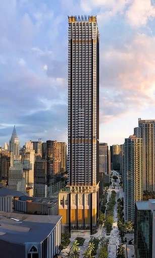 A tall, modern skyscraper with a sleek design and golden accents, surrounded by city buildings under a partly cloudy sky.