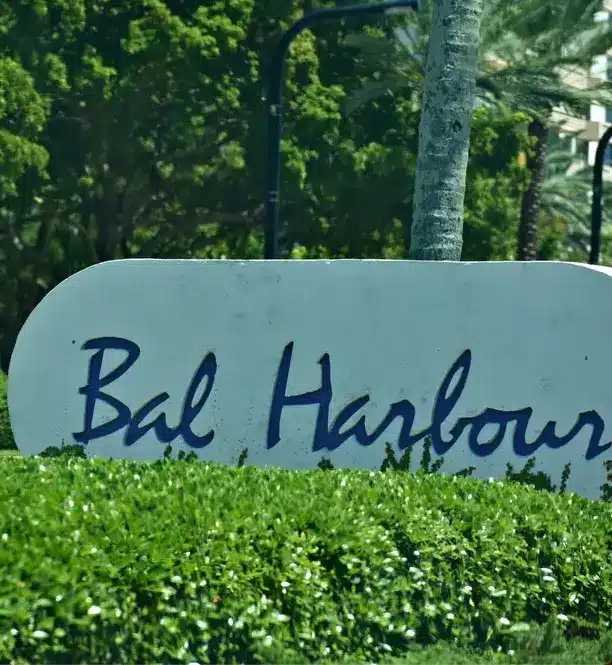 Bal Harbour entrance sign surrounded by manicured hedges and palm trees, marking the entrance to the coastal village in Miami-Dade County.