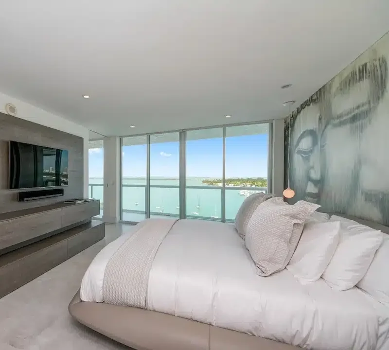 Modern luxury condominium bedroom with floor-to-ceiling windows and panoramic Biscayne Bay views in Belle Isle, Miami Beach.