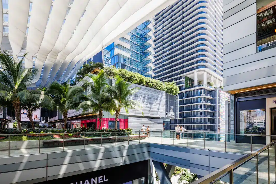 Brickell City Centre outdoor shopping promenade with modern high-rise towers, palm trees, luxury storefronts, and shaded walkways.