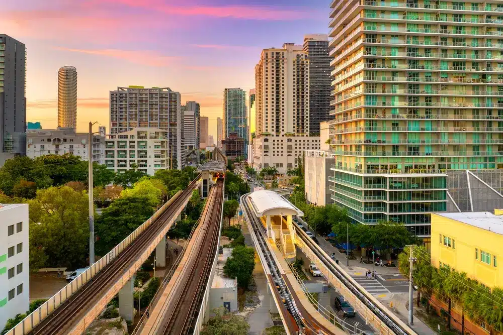 Metrorail line running through Brickell at sunset with high-rise buildings, urban streets, and Miami’s modern financial district skyline.