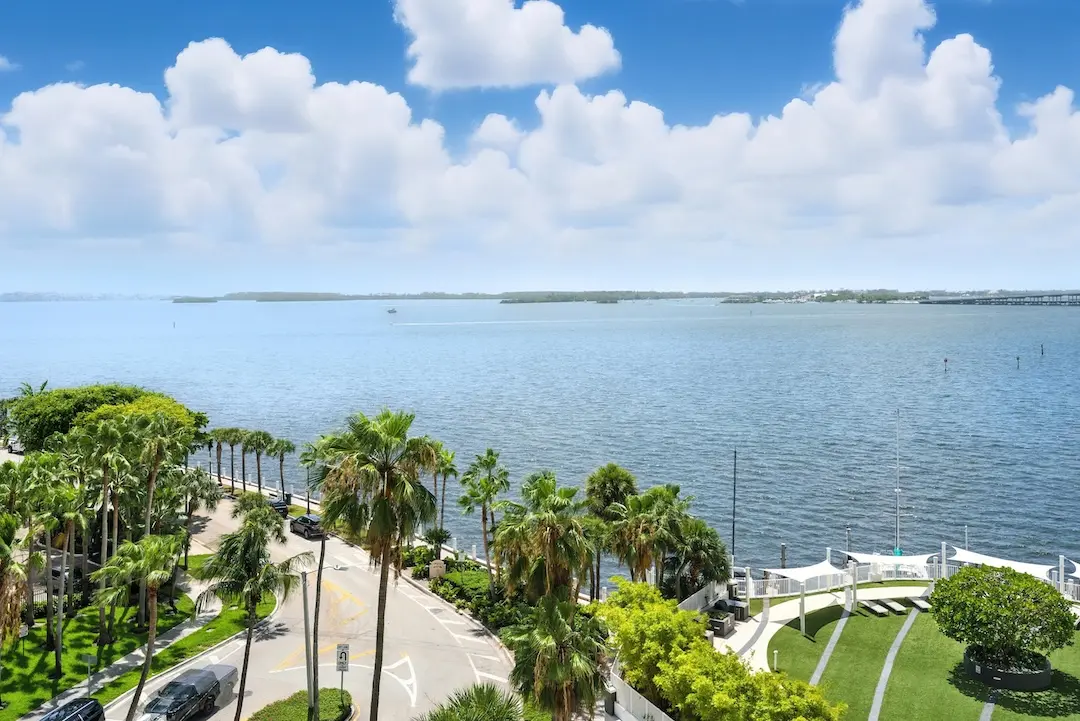 Waterfront view of Brickell overlooking Biscayne Bay, with palm-lined streets, bayfront walkways, and open water extending toward Key Biscayne.