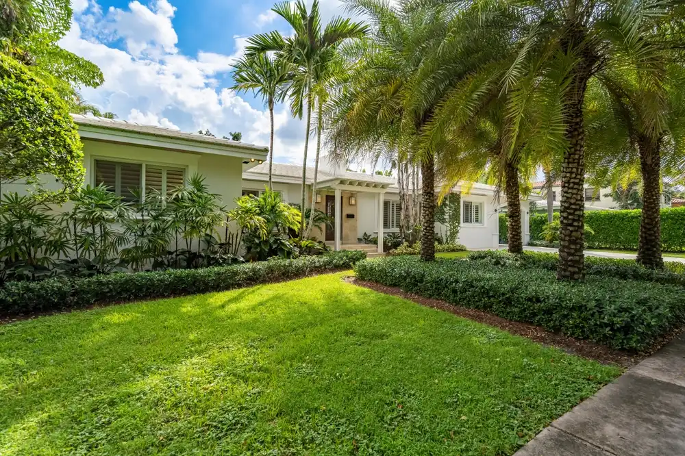 Single-family home in Coral Gables with manicured lawn, palm trees, tropical landscaping, and classic Florida architectural style.