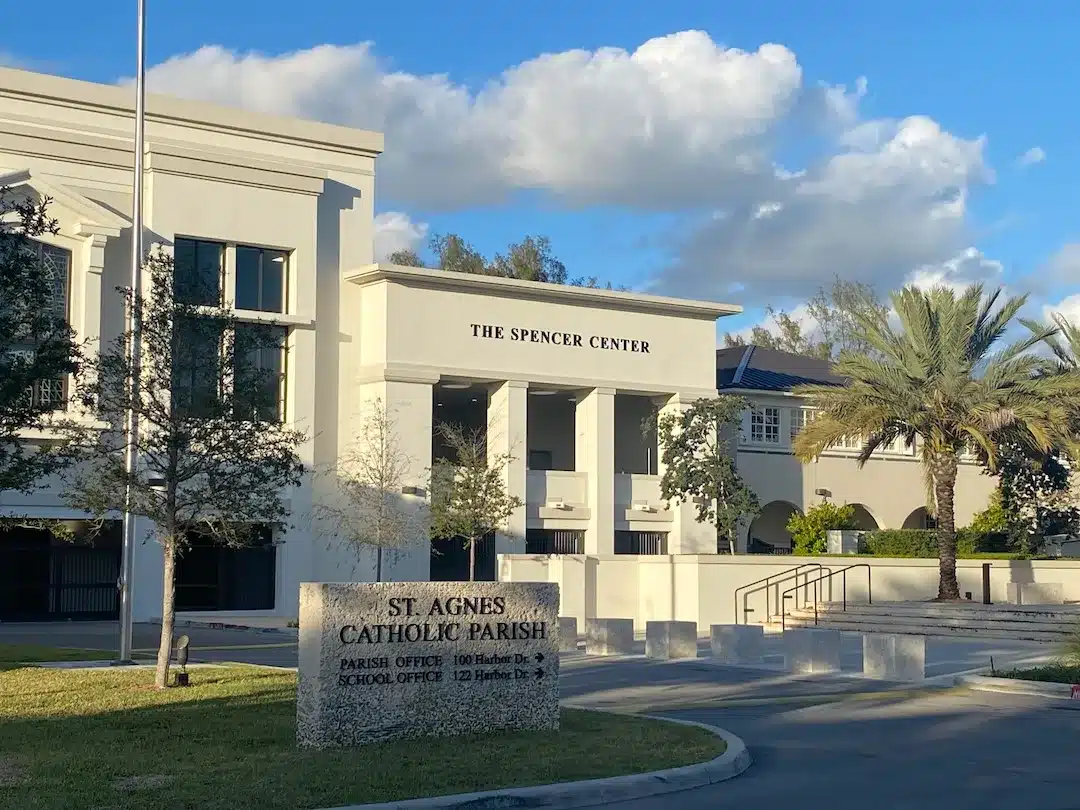 St. Agnes Catholic School, featuring a white Mediterranean-style building, palm trees, and landscaped grounds under a bright blue sky.