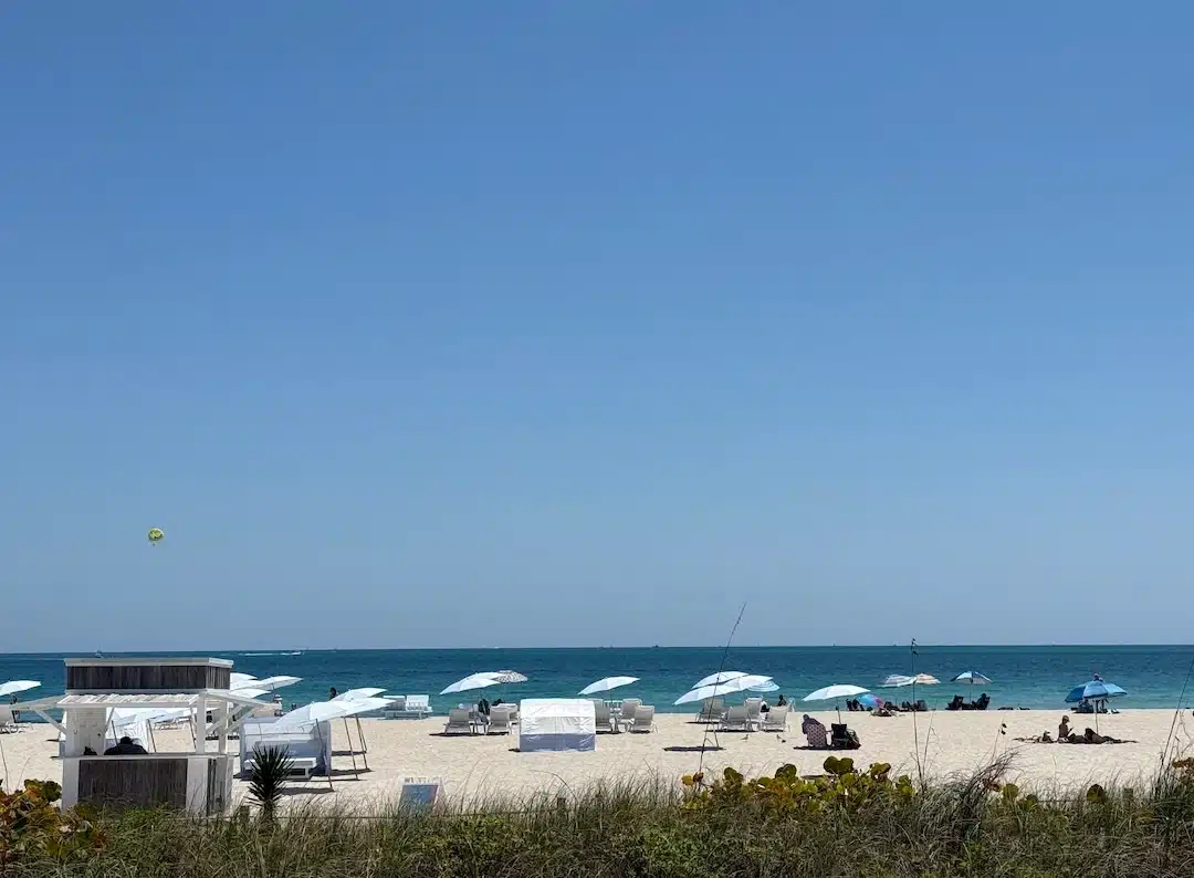 Relaxing day on Miami Beach with white umbrellas, sandy shoreline, and the Atlantic Ocean stretching to the horizon.