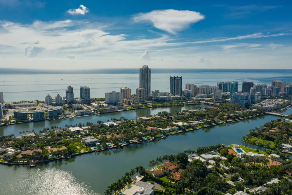Aerial view of Mid-Beach Miami Beach with bayfront homes, lush islands, canals, and oceanfront high-rise condos along the Atlantic coastline.