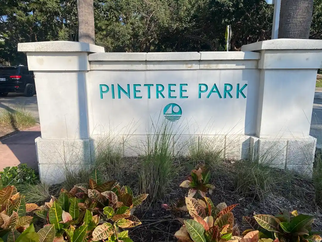 Pinetree Park entrance sign in Miami Beach surrounded by landscaping and palm trees in a quiet residential neighborhood.