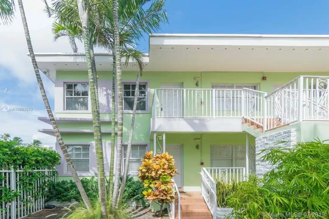 Pastel-colored Art Deco–style residential building in South Beach, Miami with balconies, palm trees, and classic architectural details.