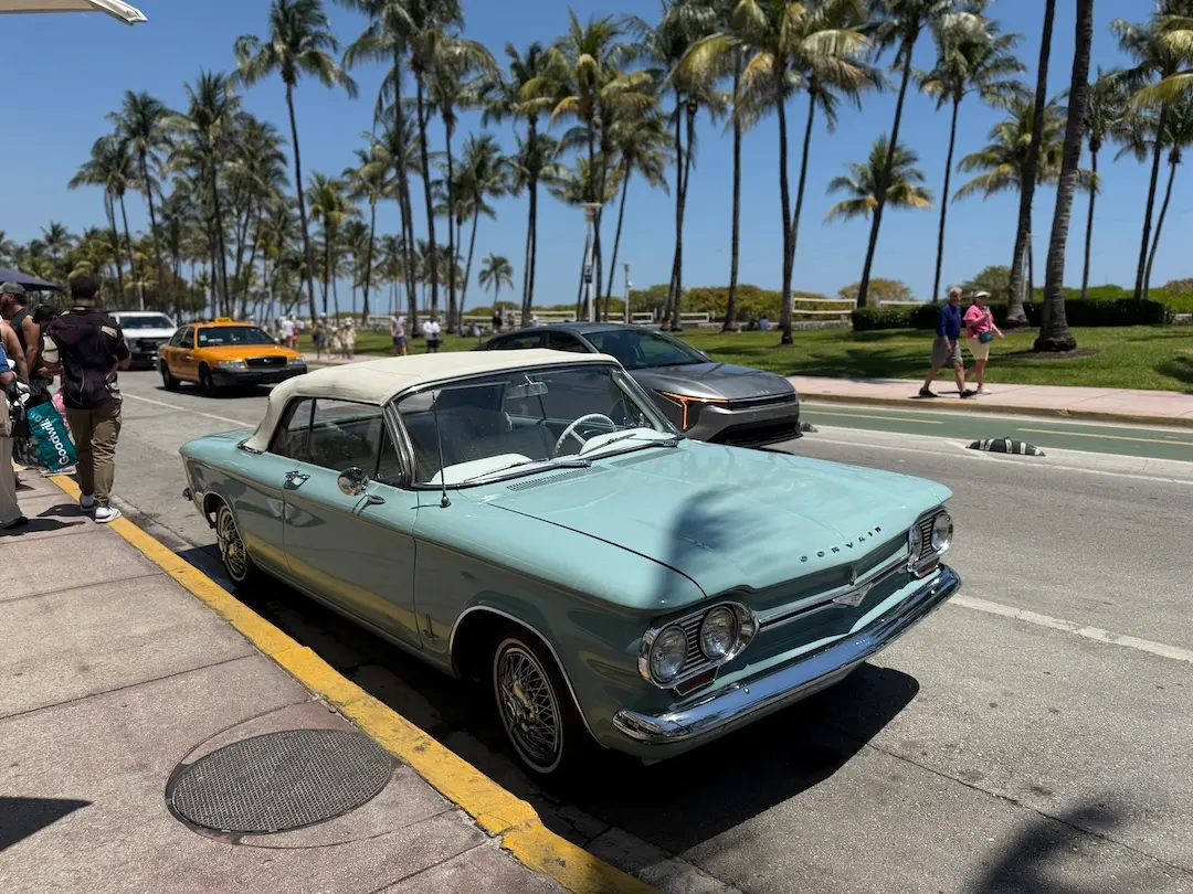 Classic car parked in South Beach Miami near palm trees and the beach.